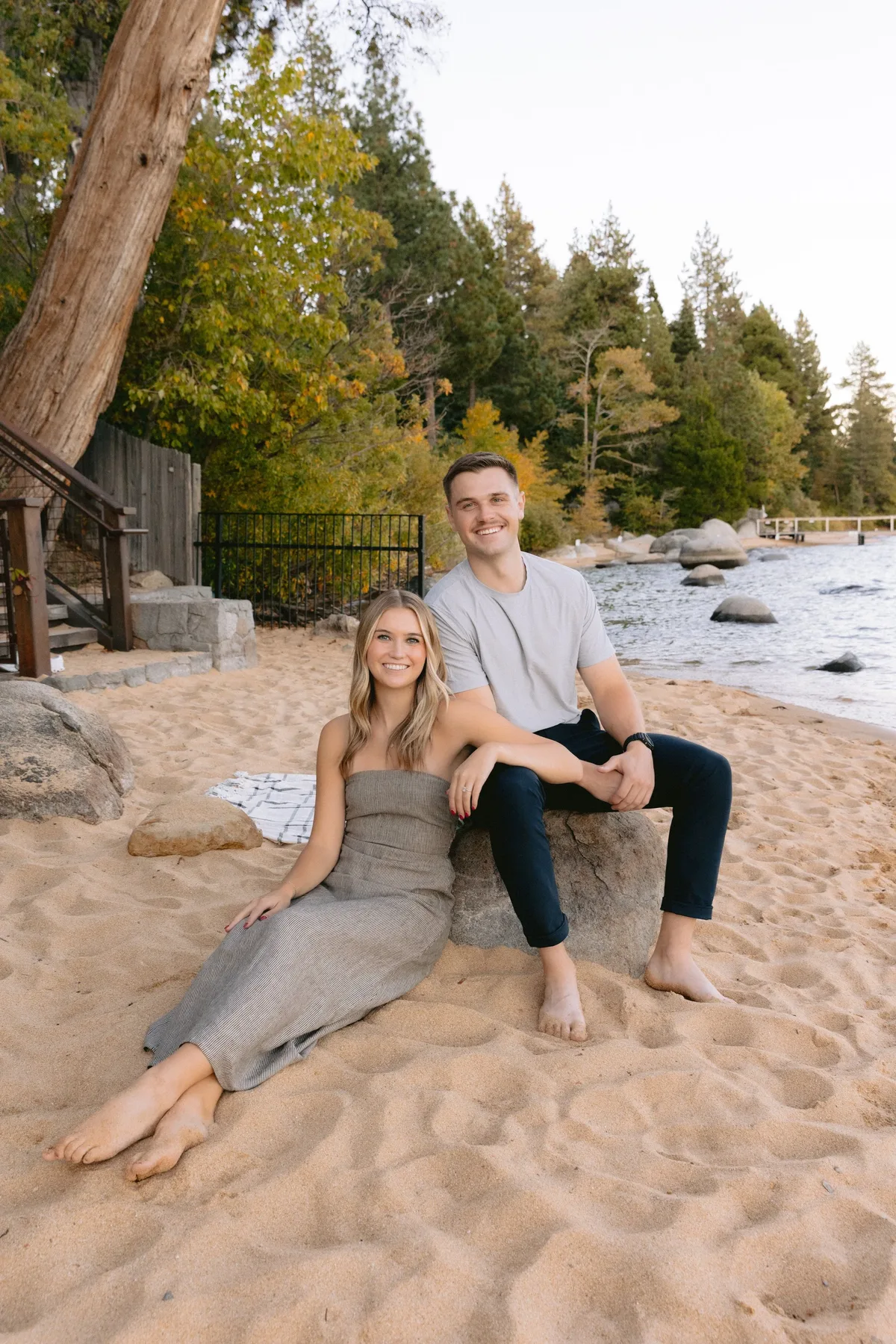 Engaged couple sitting together on a Lake Tahoe beach