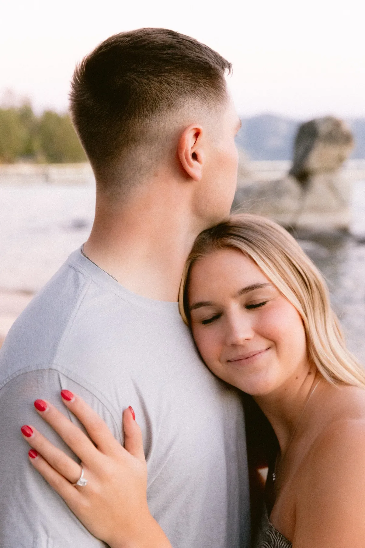 Woman resting against her fiance beside Tahoe granite boulders