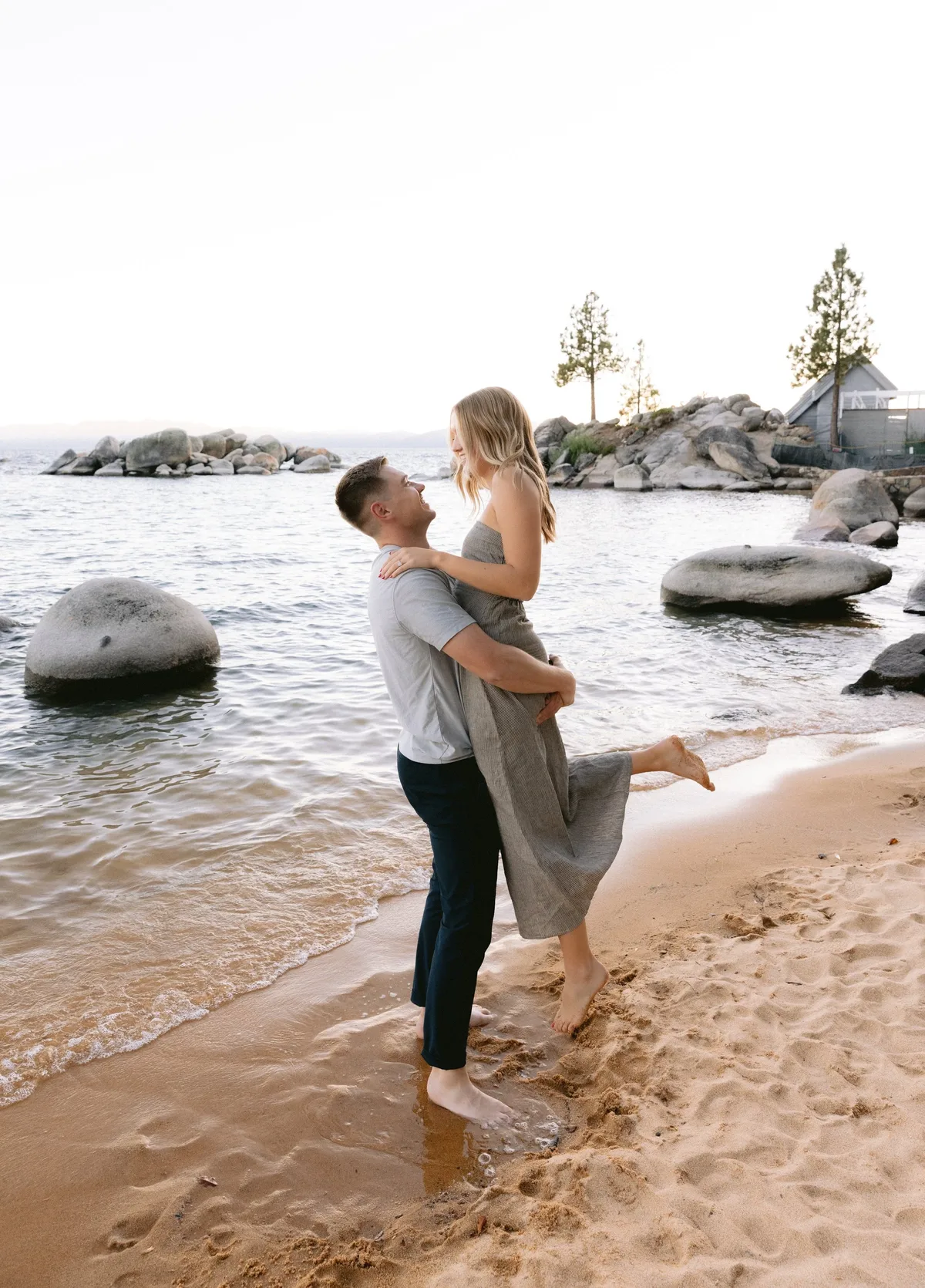 Man lifting his partner at the water’s edge on Lake Tahoe