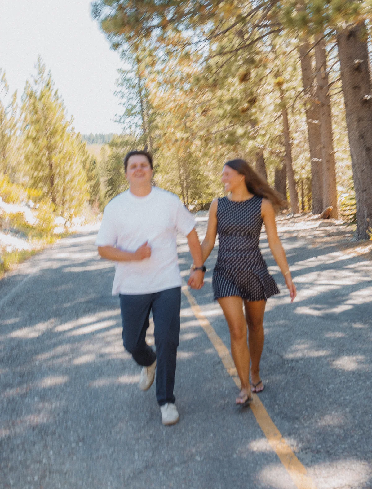 Couple running hand in hand along a forest road