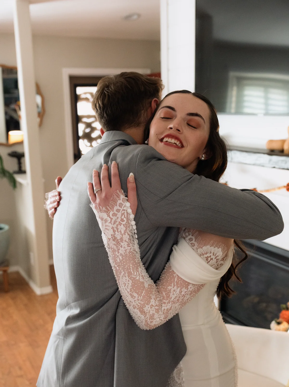 Bride hugging the groom with her eyes closed at their first look in the living room