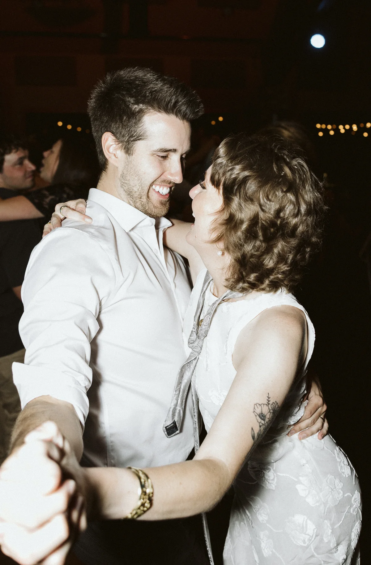 Bride and groom dancing close under string lights at their reception