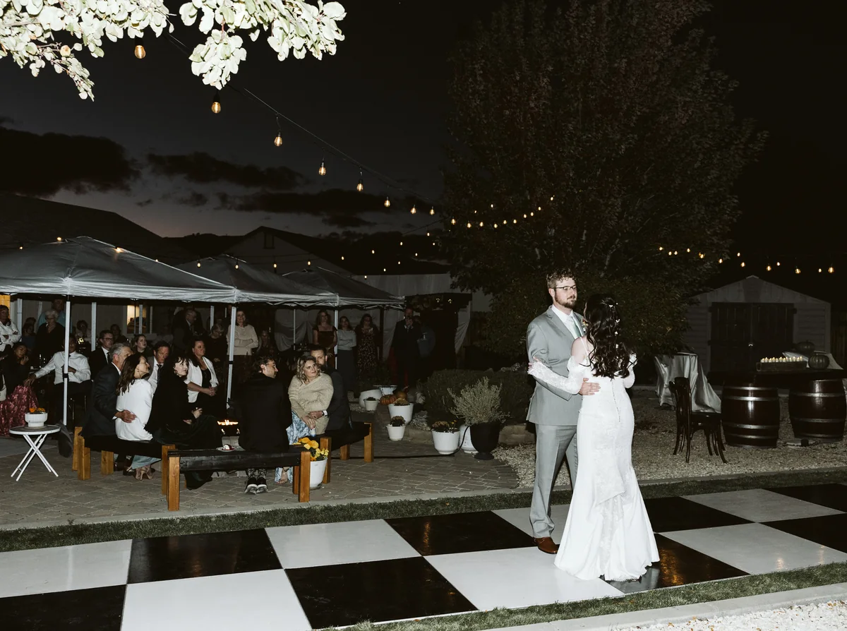 First dance on a black and white checkered dance floor under string lights