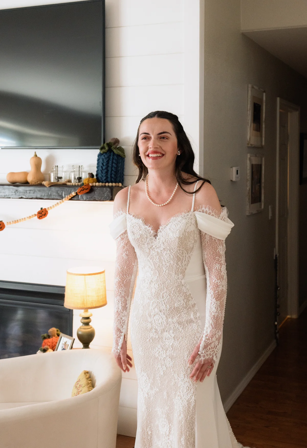Bride in a lace gown smiling in her living room before the first look
