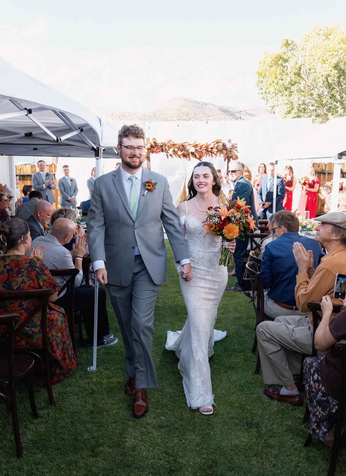 Newlyweds walking back up the aisle hand in hand as guests applaud
