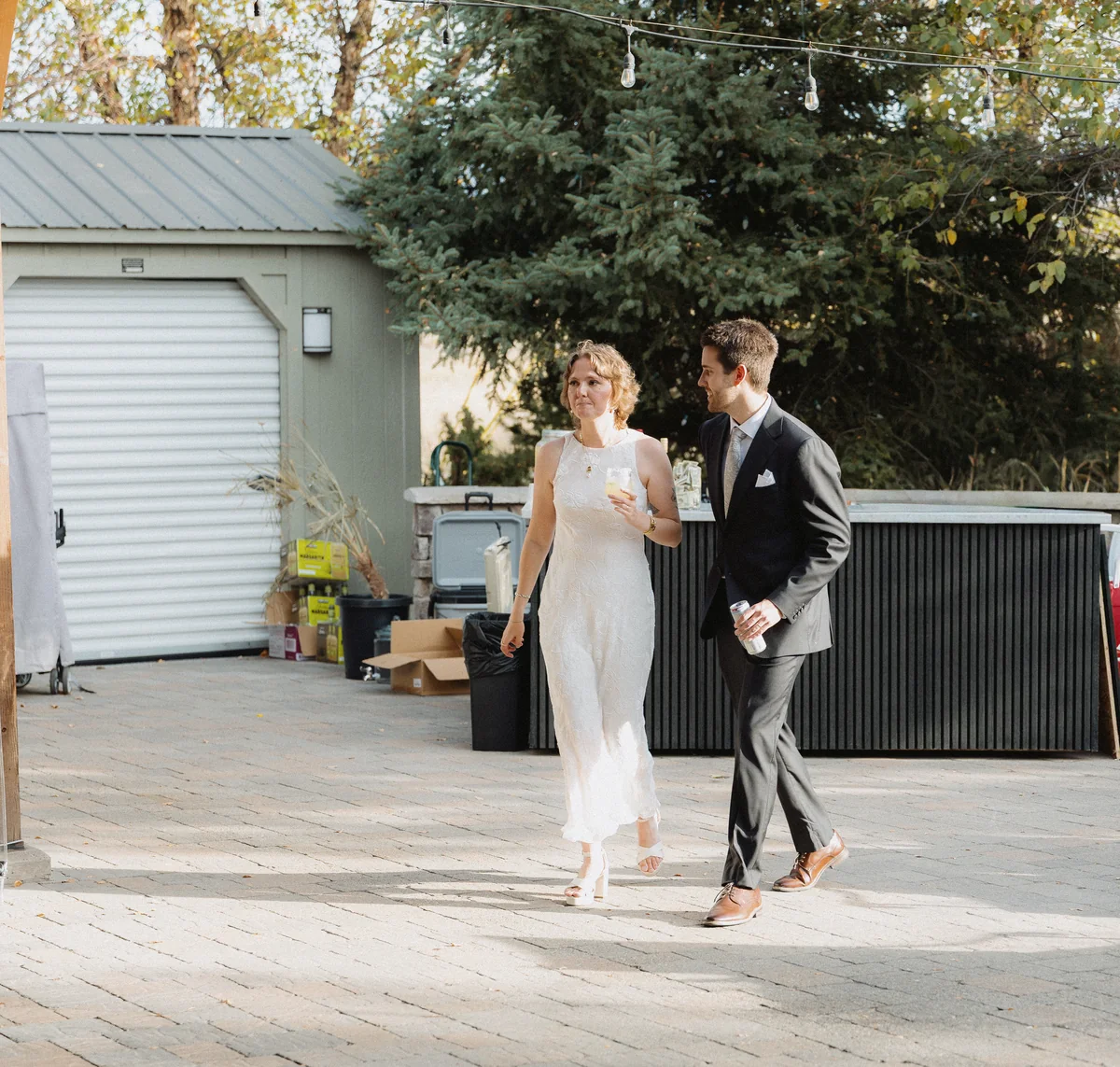 Bride and groom walking together across a sunny patio