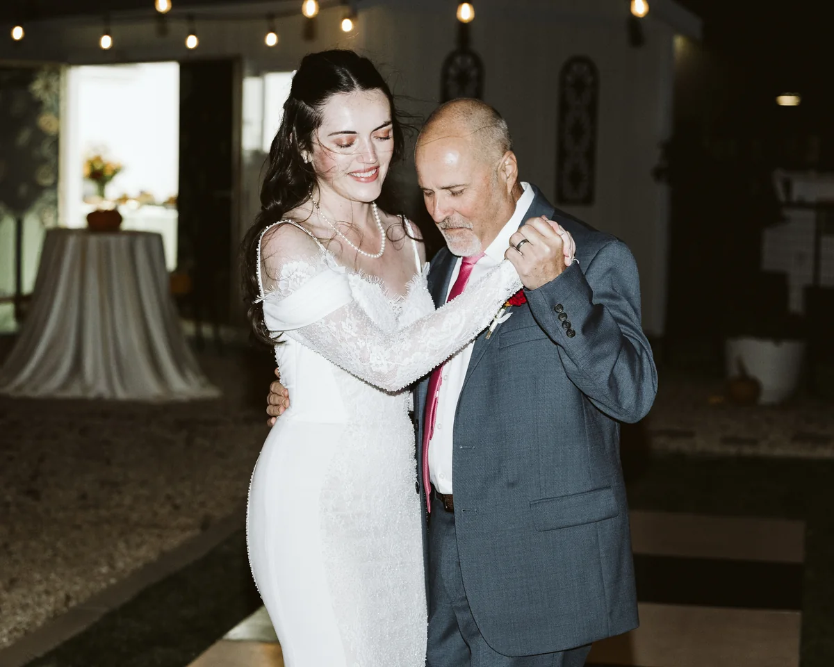 Bride smiling during the father-daughter dance under string lights